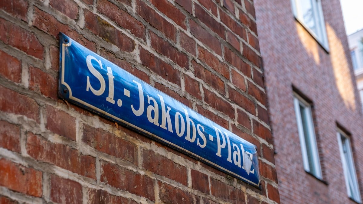 a blue street sign mounted to a brick wall